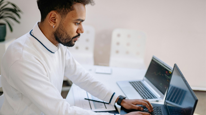 Man working at desk with 2 laptops