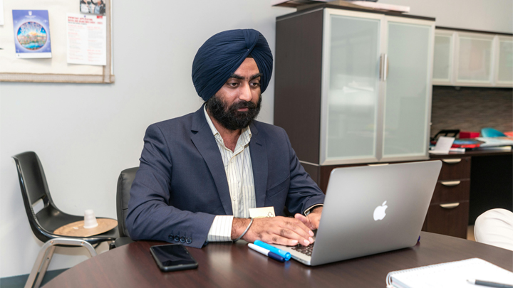 Man in turban working at desk with laptop