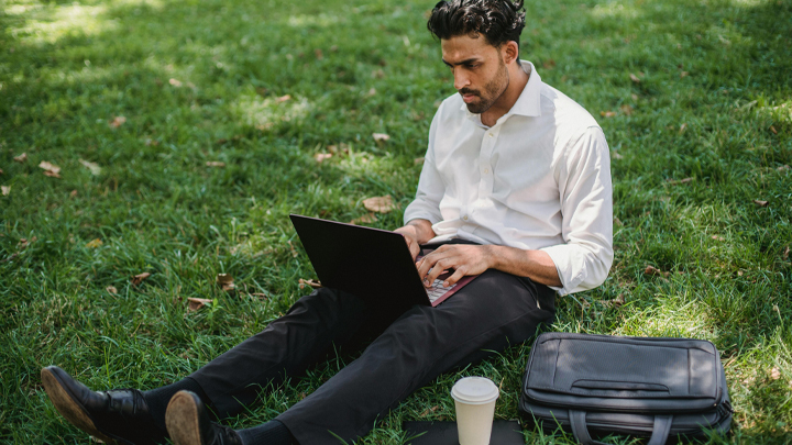 Man working on laptop whilst sat in a park