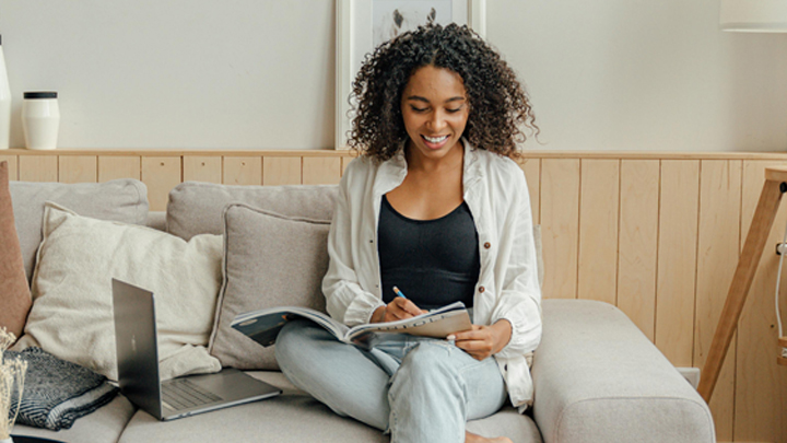 Woman working from home, sat on sofa with laptop