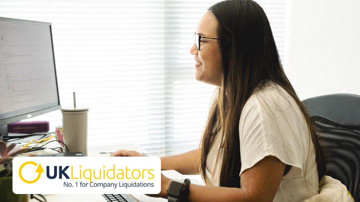 Woman at desk working, with UK Liquidators logo in bottom left corner