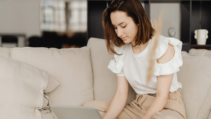 Woman sat on sofa with laptop