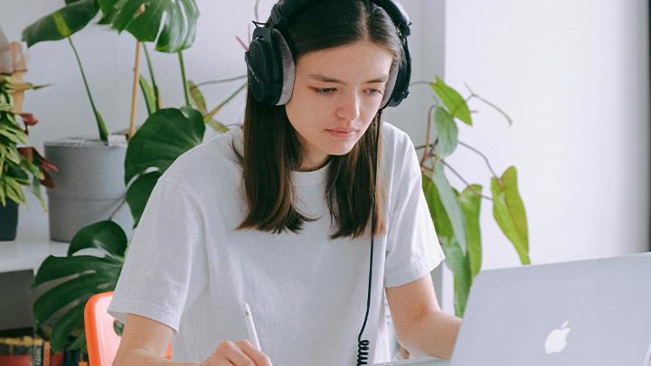 Woman wearing headphones and working on laptop