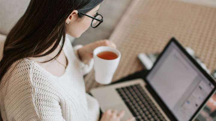 Women with cup of tea, working on laptop