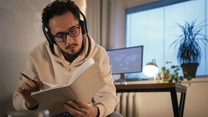 man looking in book, wearing headphones