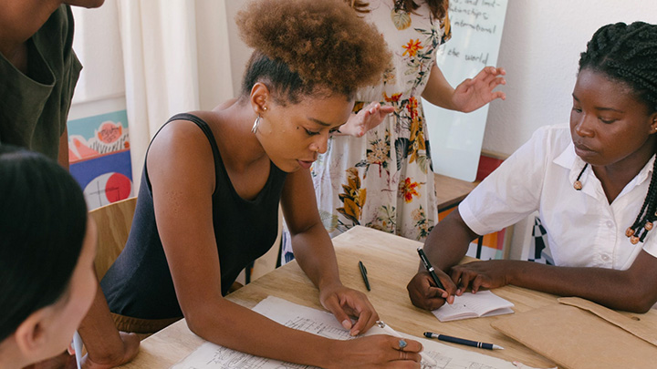 People working around a table, writing on paper